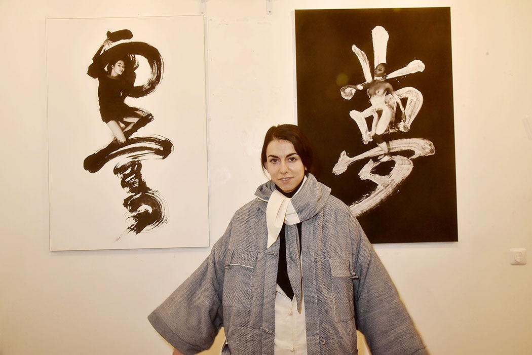 Galerie Ephemere Expo Deyi X Chris Calvet La Styliste Adriana Gagigas de Deyi pose devant des calligraphies de Chris Calvet