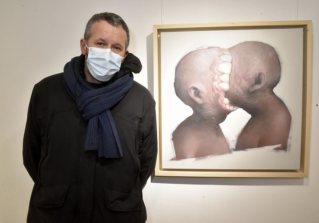 Bom.K pose avec un portrait decannibales durant pendant Ma Thématiques Expo Bom.K à la Galerie Joël Knafo